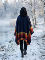Poncho Douceur Rayé – coloris Marine et orange, porté au bord d'un lac givré, capuche en maille relevée, vu de dos