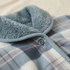 Châle-Plaid Câlin – gros plan sur le tissu écossais gris bleuté, le col doublé de polaire et le bouton